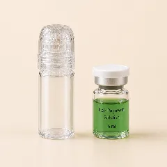 The microneedle with its cap beside a single vial of green serum